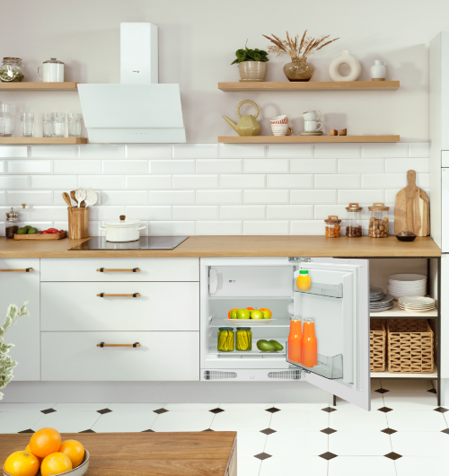 Biała lodówka marki Amica zabudowana w jasnej kuchennej zabudowie