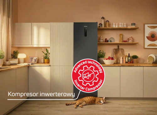 Lodówka Amica w jasnej kuchni, kot na podłodze, napis „Kompresor inwerterowy” i czerwona ikona technologii inwerterowej
